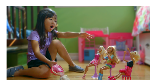 Little girl sitting on the floor playing with barbie dolls