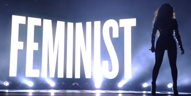 Beyonce at the 2014 vma's on stage with the word feminist behind her during her perfromance